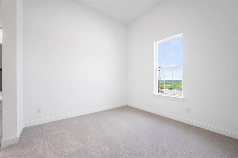 Spare bedroom featuring light carpet