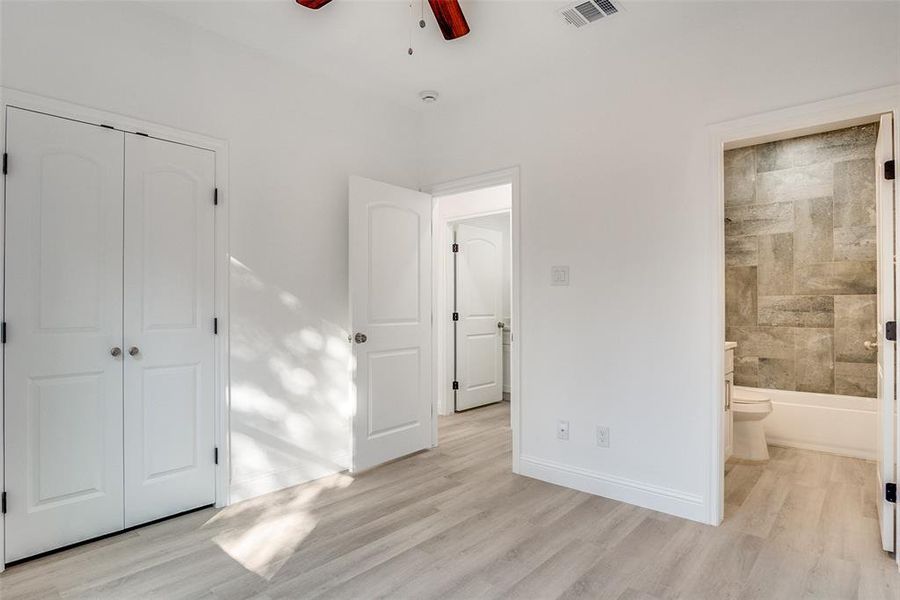 Unfurnished bedroom featuring a closet, light wood-style floors, a ceiling fan, and ensuite bath Unfurnished bedroom featuring a closet, light wood-style floors, a ceiling fan, and ensuite bath