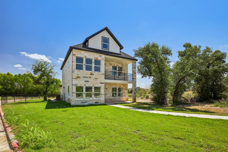 Natural stone masonry and a private upper balcony define this striking multi-level exterior architecture.