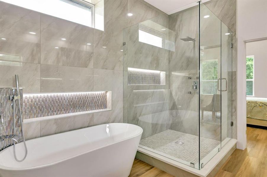 Modern bathroom featuring a frameless glass shower enclosure, a freestanding soaking tub, and large format wall tiles Modern bathroom featuring a frameless glass shower enclosure, a freestanding soaking tub, and large format wall tiles