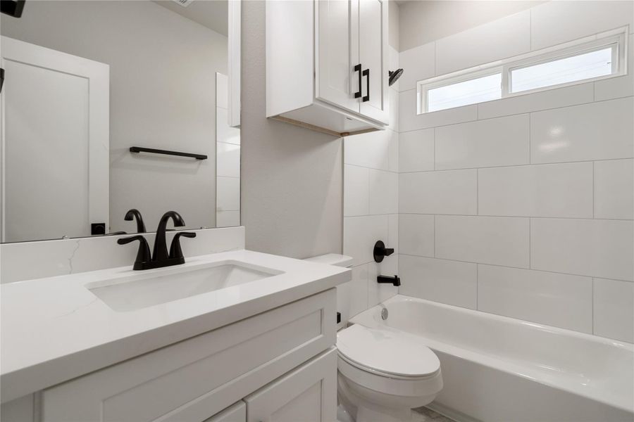 This bathroom features a modern design with clean white tiles, a sleek vanity with a black faucet, and a combined shower-tub. The room is well-lit with a small window for natural light. This bathroom features a modern design with clean white tiles, a sleek vanity with a black faucet, and a combined shower-tub. The room is well-lit with a small window for natural light.