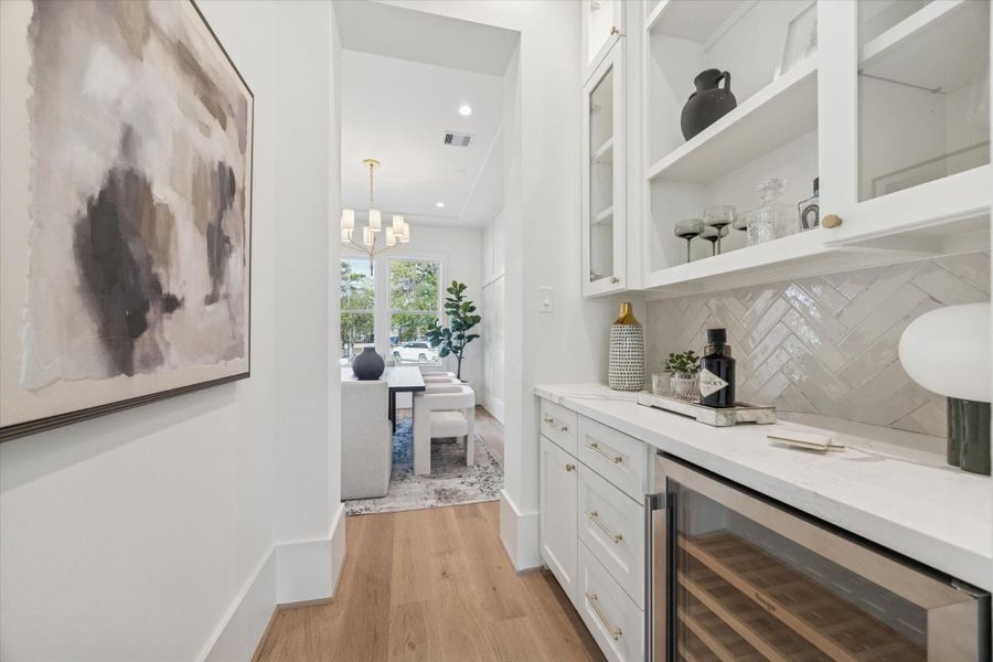 Butler’s Pantry — Beautiful built-in cabinetry with glass uppers, a stylish backsplash, and a beverage fridge—perfect for serving and storage.