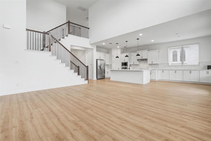 Unfurnished living room with light wood-style floors, a high ceiling, and recessed lighting