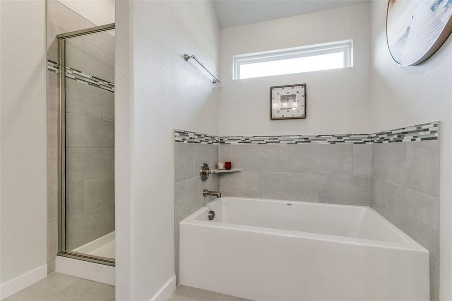 Primary bathroomwith independent shower and bath and tile patterned floors