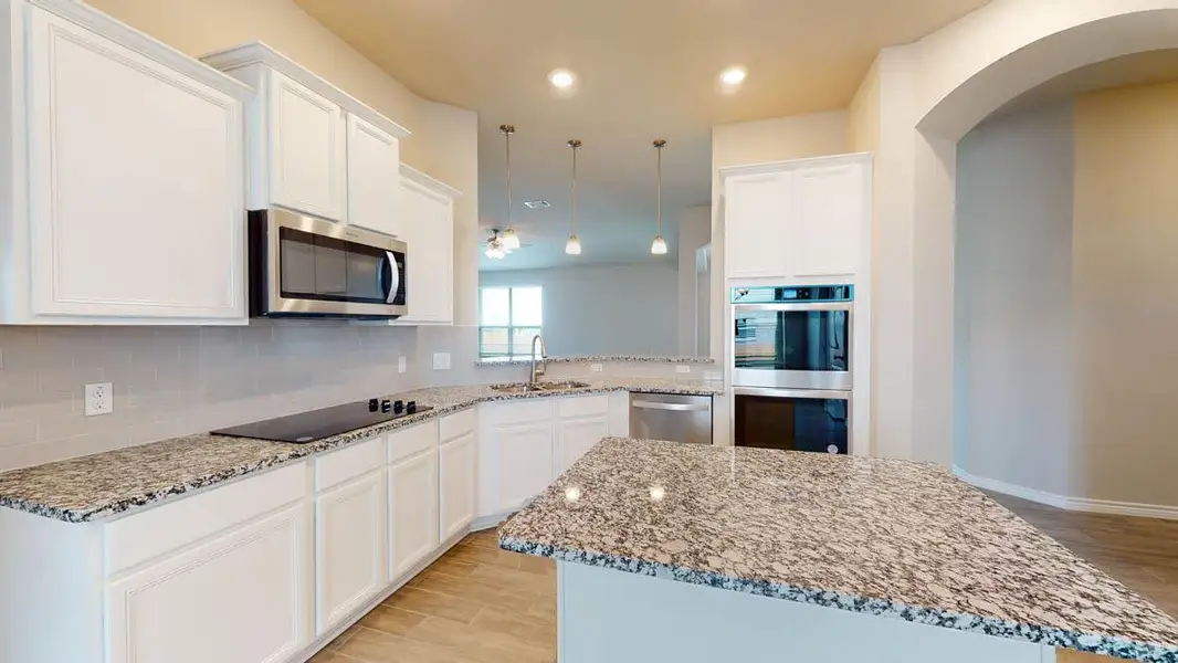 Kitchen with light stone countertops, white cabinets, stainless steel appliances, light wood-style flooring, and a center island