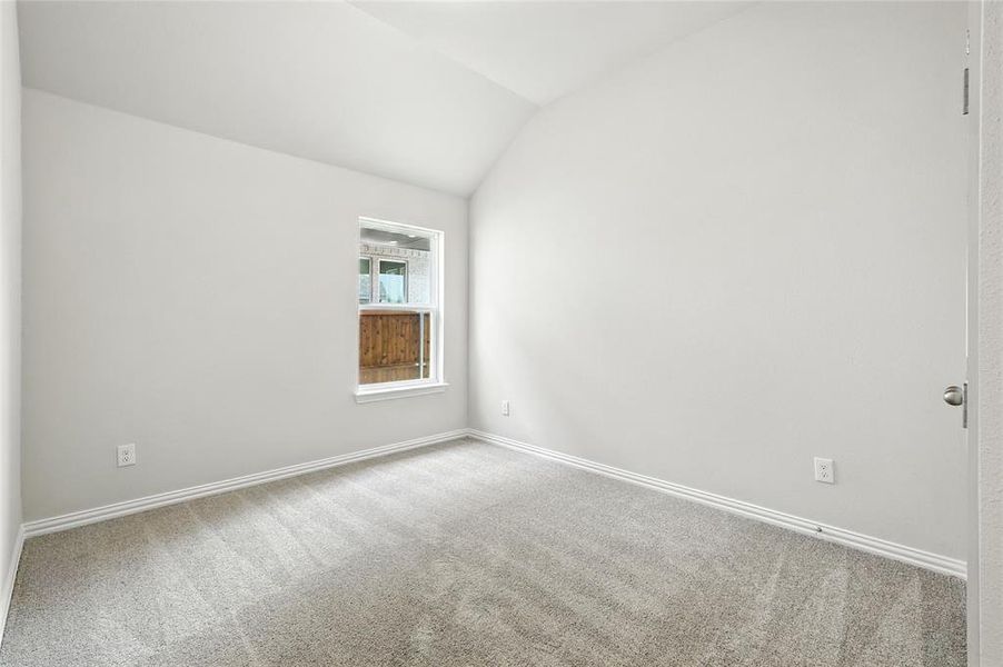 Unfurnished room featuring light carpet and lofted ceiling