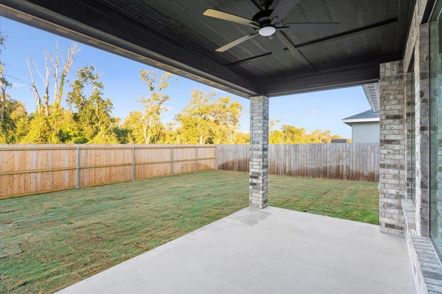 Fenced backyard featuring a ceiling fan and a patio area Fenced backyard featuring a ceiling fan and a patio area