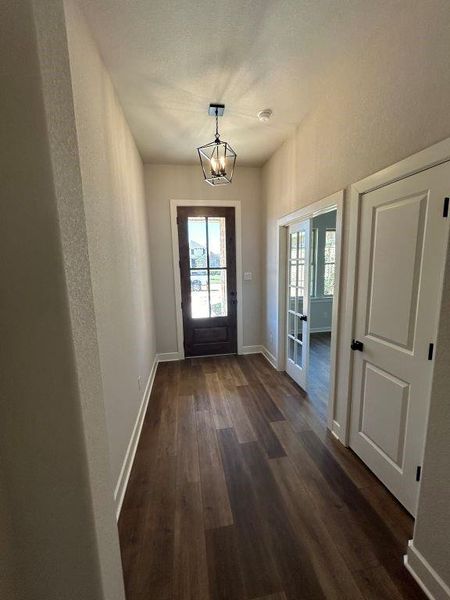 Doorway to outside with a chandelier and dark wood-type flooring