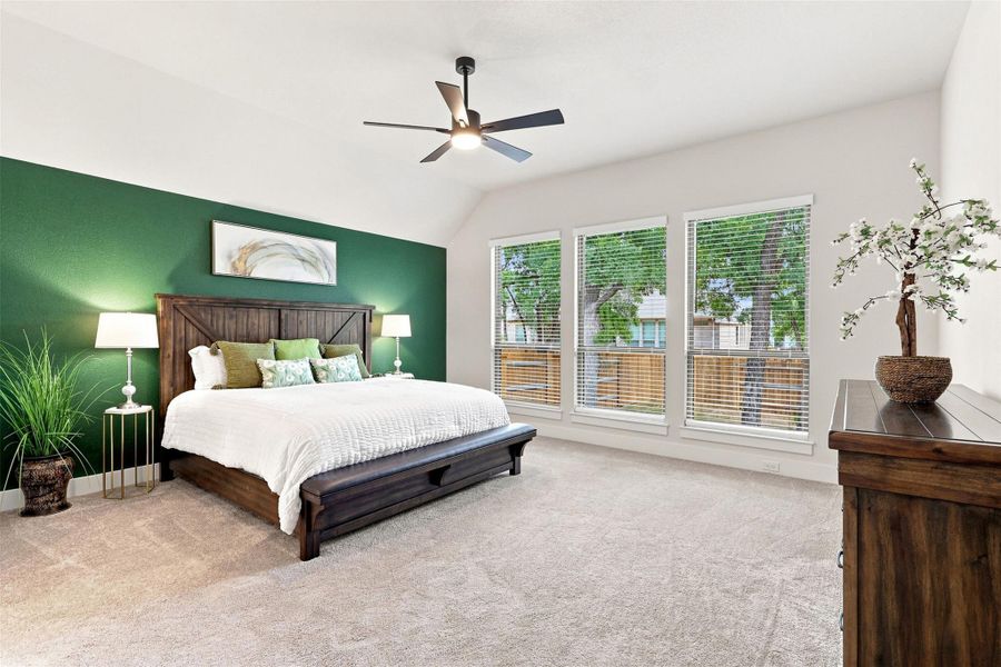 A well-lit bedroom features vaulted ceilings and ample natural light through a series of windows.