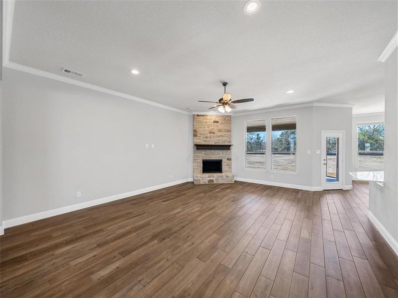 Prior listing photo. Property remains accurate - Unfurnished living room featuring crown molding, dark wood-style floors, a ceiling fan, a fireplace, and recessed lighting