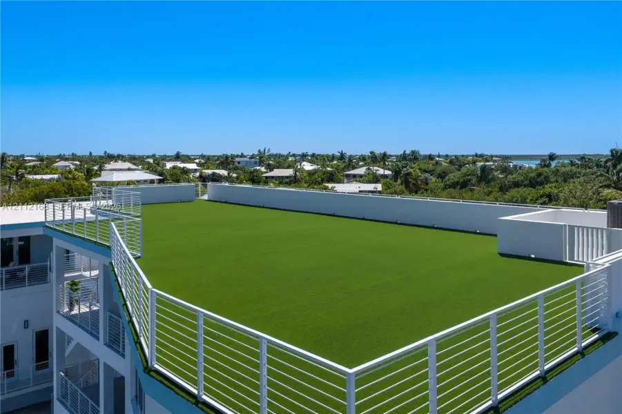 Rooftop terrace featuring artificial turf flooring, white metal railings, and perimeter wall lighting Rooftop terrace featuring artificial turf flooring, white metal railings, and perimeter wall lighting