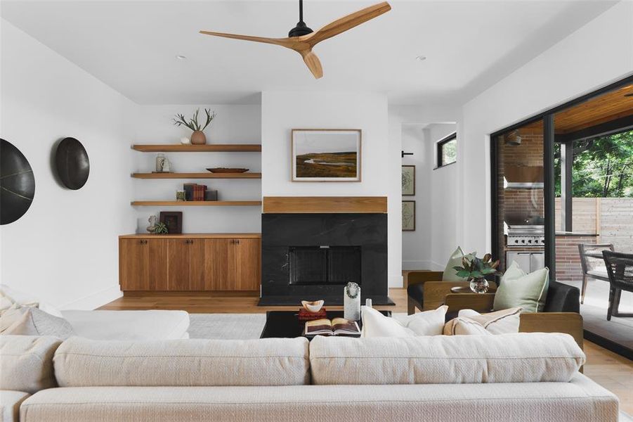 At the center of the home, the spacious living room features a striking, granite and white oak framed fireplace flanked with reeded white oak cabinetry.