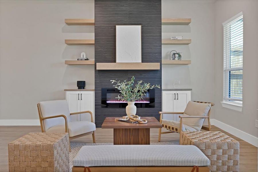 Sitting room with baseboards, light wood-type flooring, and a fireplace Sitting room with baseboards, light wood-type flooring, and a fireplace