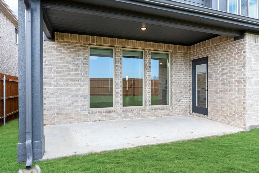 Covered back patio with concrete slab, brick exterior, large windows, and back door leading to green lawn. Covered back patio with concrete slab, brick exterior, large windows, and back door leading to green lawn.