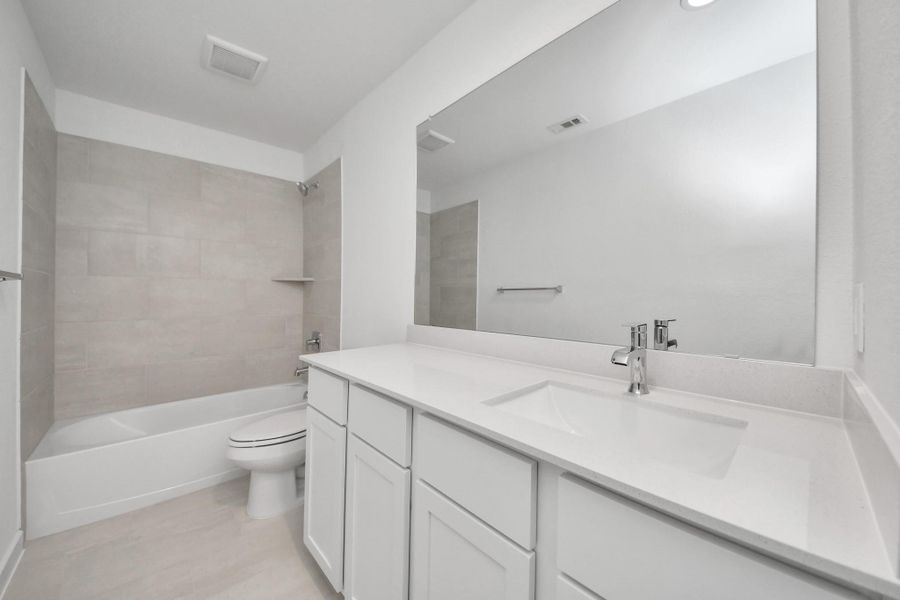 Secondary bath features tile flooring, bath/shower combo with tile surround, light stained wood cabinets, beautiful light countertop. Secondary bath features tile flooring, bath/shower combo with tile surround, light stained wood cabinets, beautiful light countertop.