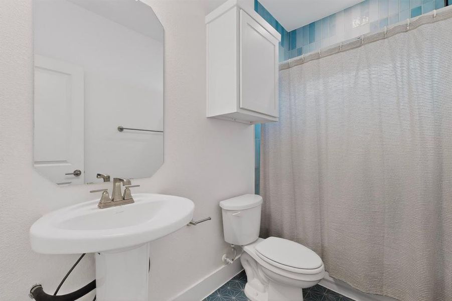 Bathroom featuring a pedestal sink, brushed nickel faucet, wall-mounted mirror, and cabinet storage Bathroom featuring a pedestal sink, brushed nickel faucet, wall-mounted mirror, and cabinet storage