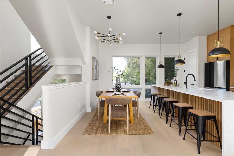 Clean lines and light wood flooring define this open, contemporary dining and kitchen space.