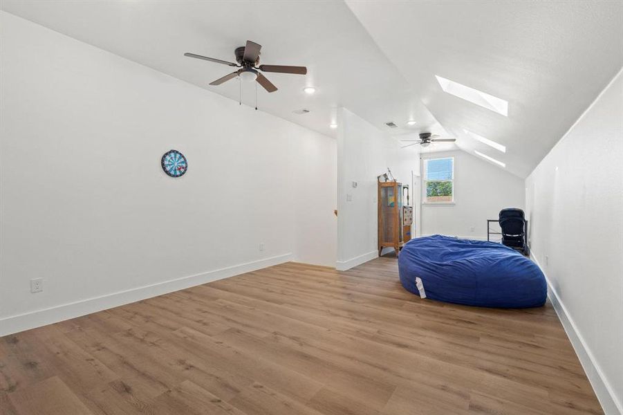 Additional living space featuring a ceiling fan, lofted ceiling, wood finished floors, a skylight, and recessed lighting
