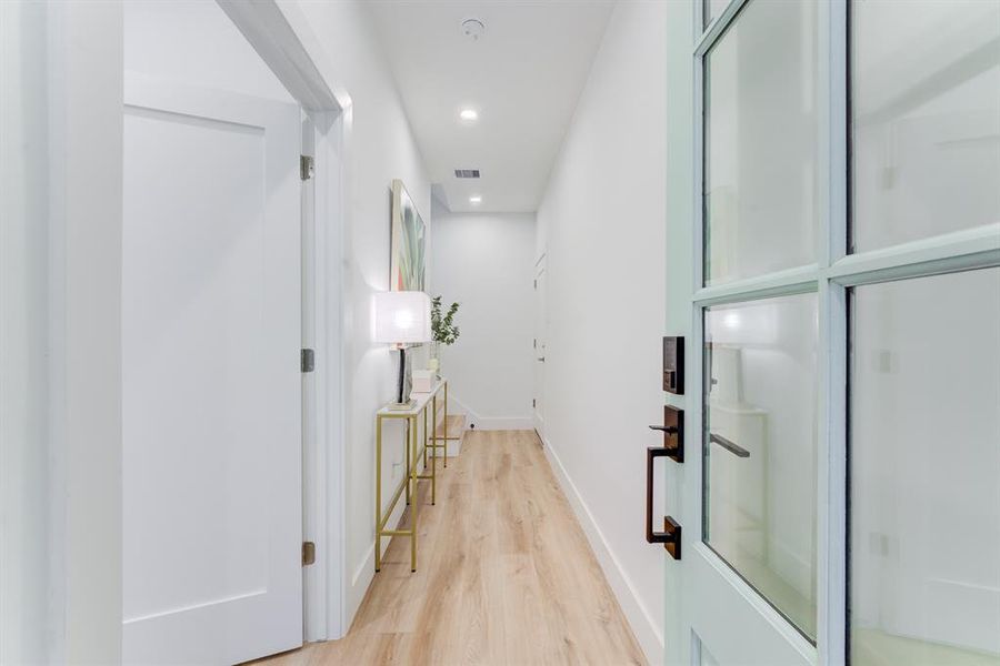 The front entryway features recessed lighting, luxury vinyl plank flooring, and a full bedroom and ensuite bathroom to the left of the doorway.