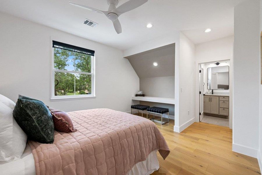 A naturally illuminated bedroom offers blonde wood flooring and convenient access to a private bathroom. A naturally illuminated bedroom offers blonde wood flooring and convenient access to a private bathroom.