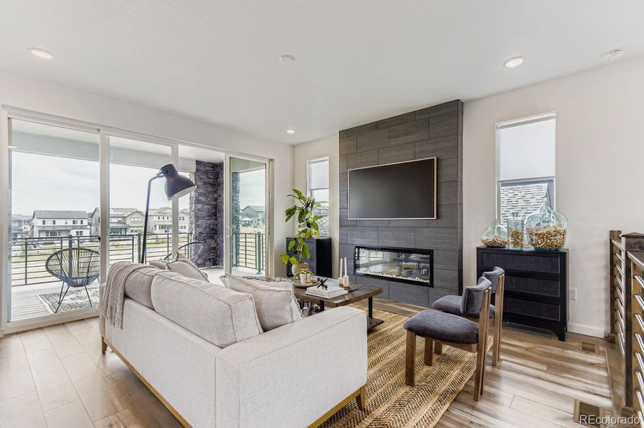 The inviting living room centers around a custom tile fireplace wall and opens through expansive sliding doors to an oversized balcony—creating effortless indoor/outdoor living and year-round enjoyment.