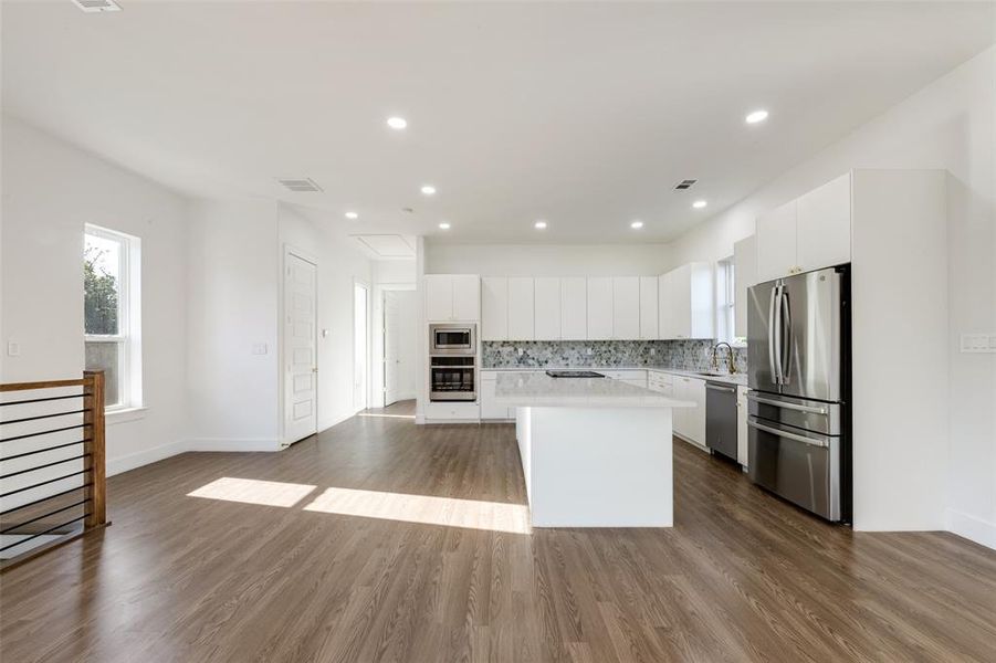 Kitchen featuring white cabinets, tasteful backsplash, dark wood finished floors, appliances with stainless steel finishes, and recessed lighting Kitchen featuring white cabinets, tasteful backsplash, dark wood finished floors, appliances with stainless steel finishes, and recessed lighting