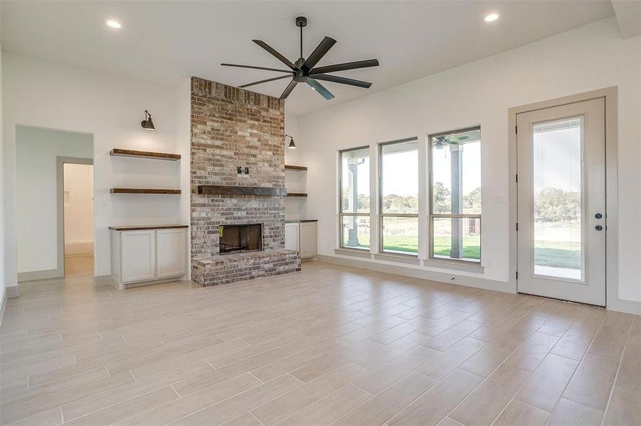 Unfurnished living room featuring a fireplace, light wood-type flooring, and ceiling fan