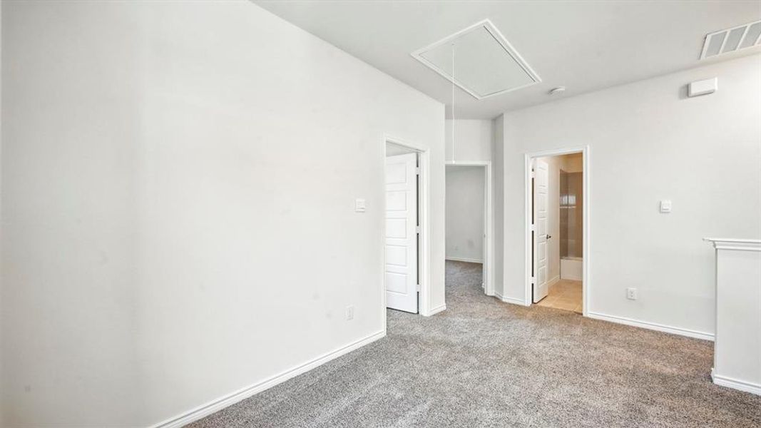 Carpeted empty room with attic access and baseboards