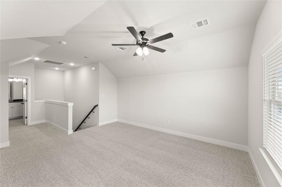 Additional living space with light colored carpet, vaulted ceiling, and ceiling fan Additional living space with light colored carpet, vaulted ceiling, and ceiling fan