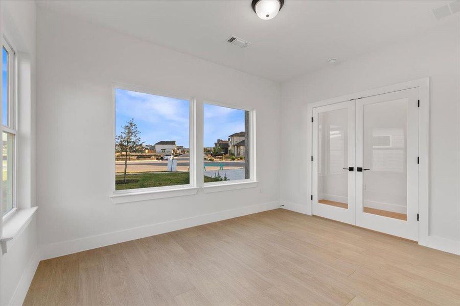 Unfurnished room with french doors and light wood finished floors Unfurnished room with french doors and light wood finished floors