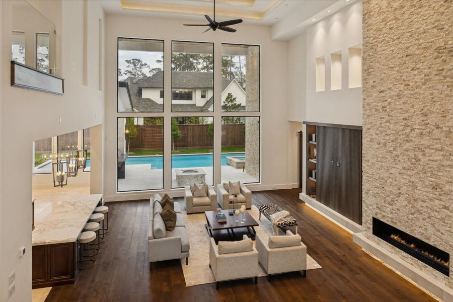 Grand two-story family room with soaring celings, a dramatic wall of glass, a striking floor to ceiling fireplace, and a seamless connection to the outdoor living spaces. Grand two-story family room with soaring celings, a dramatic wall of glass, a striking floor to ceiling fireplace, and a seamless connection to the outdoor living spaces.