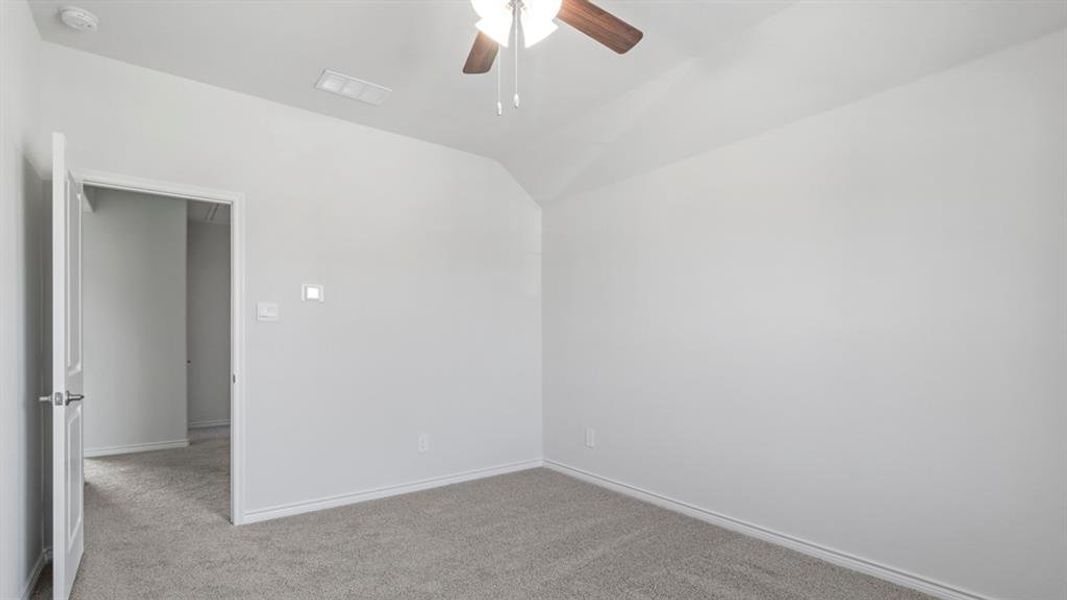 Carpeted spare room featuring a ceiling fan and lofted ceiling