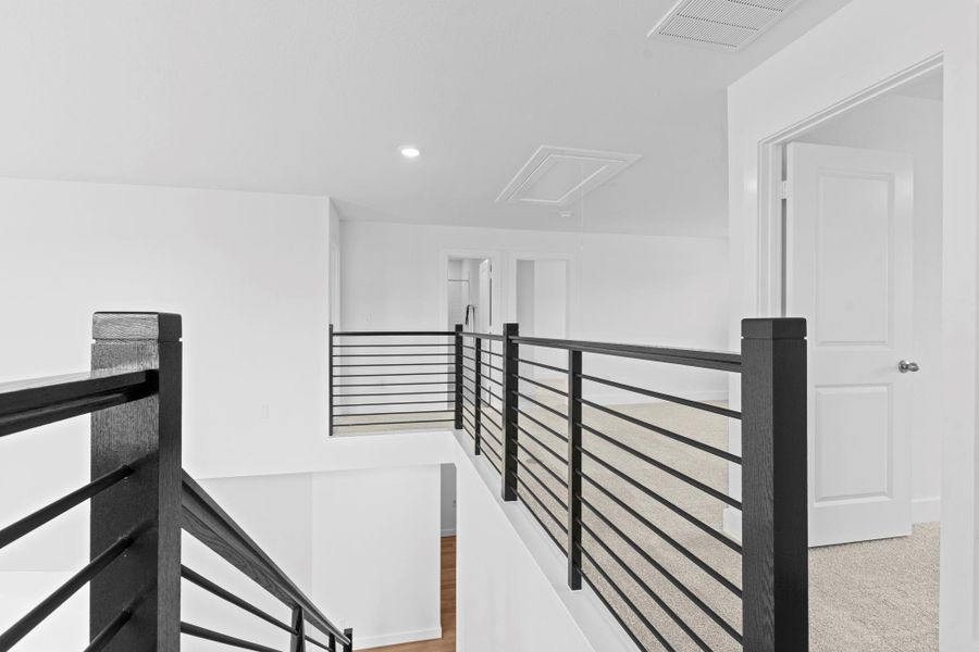 The upstairs landing features sleek wrought iron railing and plush carpet, providing an open and modern transition space between secondary bedrooms and the game room. **Image Representative of Plan Only and May Vary as Built**. The upstairs landing features sleek wrought iron railing and plush carpet, providing an open and modern transition space between secondary bedrooms and the game room. **Image Representative of Plan Only and May Vary as Built**.