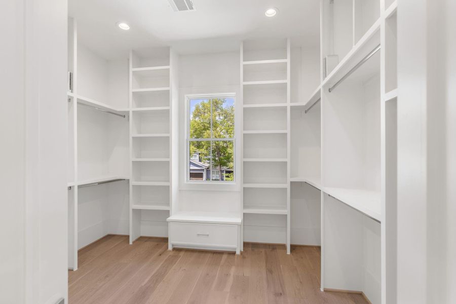 His oversized walk-in closet is outfitted with custom built-ins, open shelving, and hanging space, designed for both organization and accessibility.