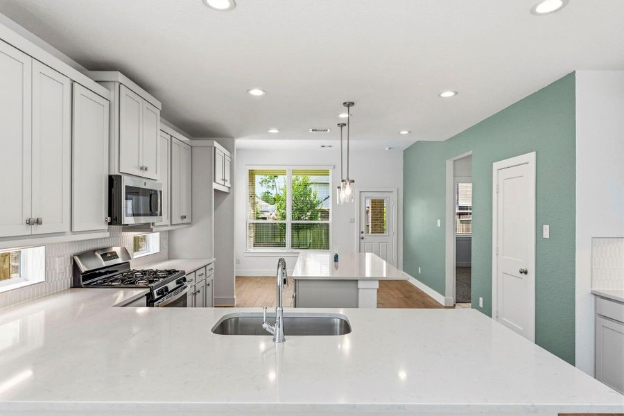 Light cabinetry, modern backsplash, and pristine white counters