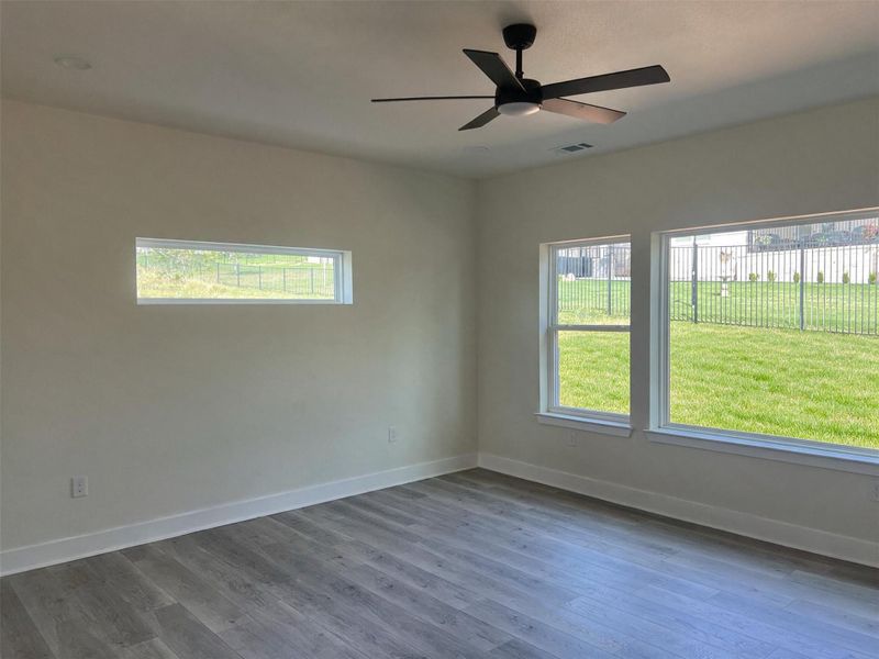A well-lit room offers pleasant backyard views and a modern ceiling fan for comfort.