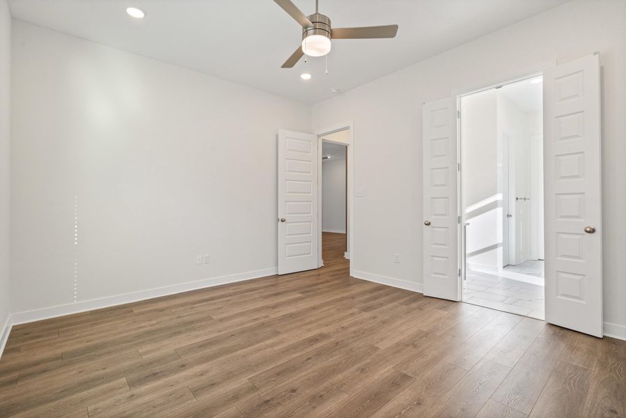 Unfurnished bedroom featuring a ceiling fan, wood finished floors, recessed lighting, and ensuite bath
