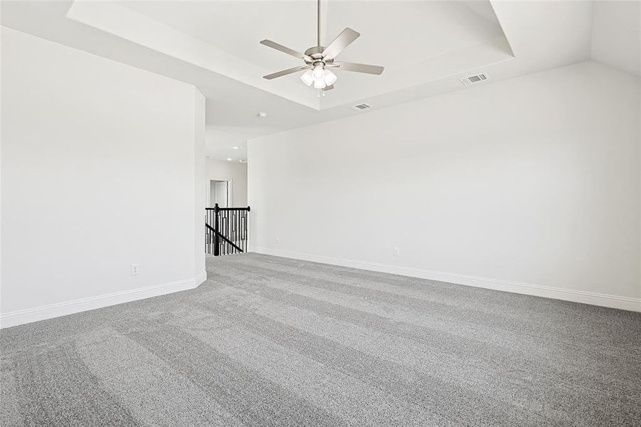 Carpeted spare room with a tray ceiling and ceiling fan