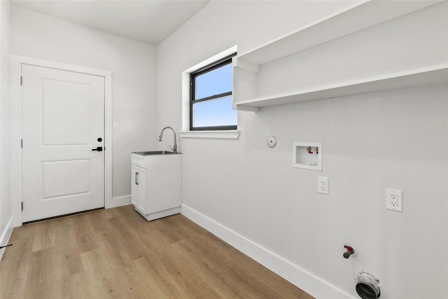 Thoughtfully designed laundry room with washer and dryer hookups, a utility sink, and convenient access to the garage.