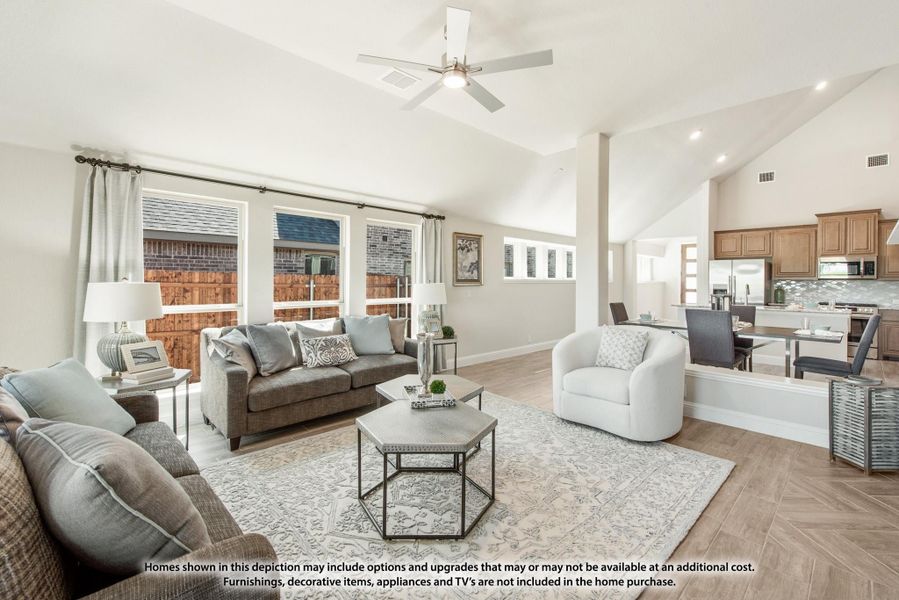Open-concept living room with vaulted ceiling, ceiling fan, gray sofas, and hardwood floors, open to kitchen dining area. Open-concept living room with vaulted ceiling, ceiling fan, gray sofas, and hardwood floors, open to kitchen dining area.