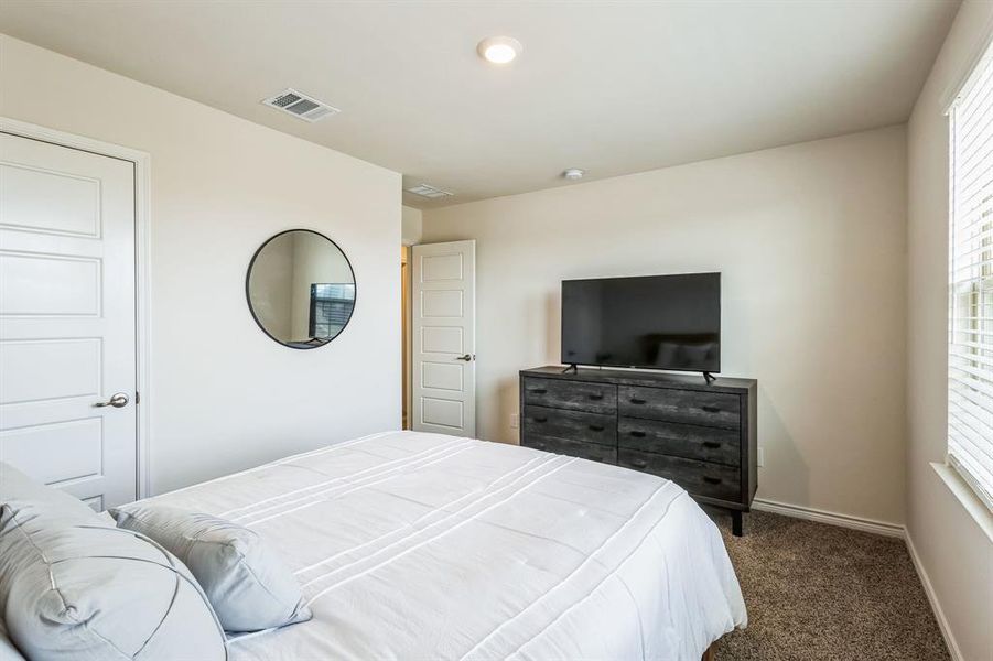 Bedroom with multiple windows and dark colored carpet