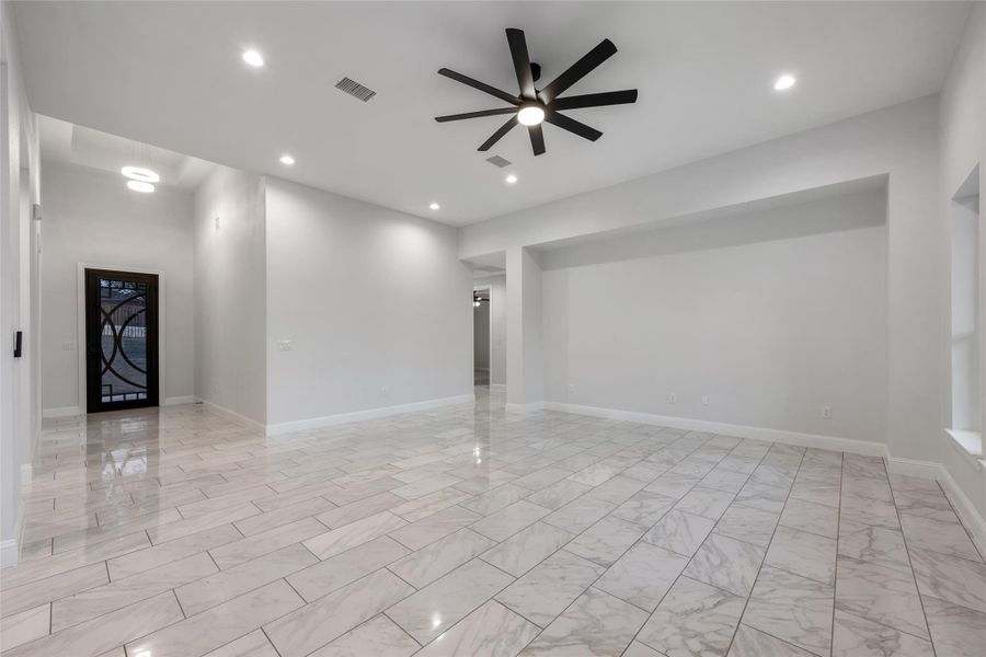 Spare room featuring a ceiling fan, recessed lighting, and light marble finish flooring