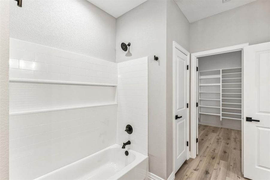 Bathroom with bathtub / shower combination and hardwood / wood-style flooring