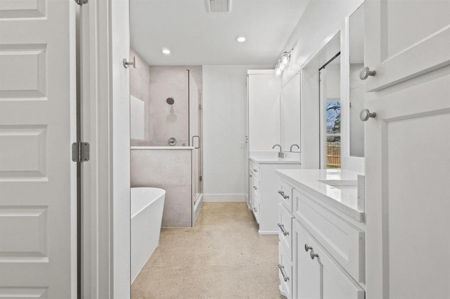 Full bath featuring a shower stall, a freestanding bath, two vanities, recessed lighting, and concrete flooring