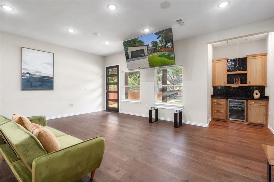 Living room featuring dark wood finished floors, recessed lighting, beverage cooler, and a bar Living room featuring dark wood finished floors, recessed lighting, beverage cooler, and a bar