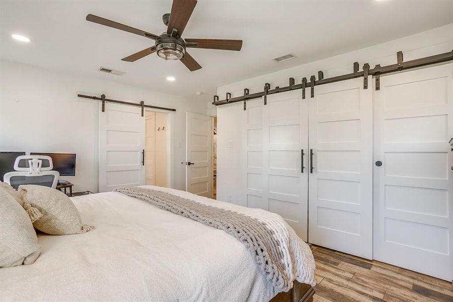 Bedroom featuring a barn door, recessed lighting, wood finished floors, ceiling fan, and a closet
