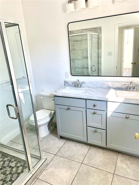 Bathroom featuring vanity, toilet, walk in shower, and tile patterned floors