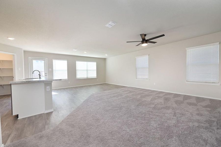 Unfurnished living room featuring ceiling fan, sink, and dark colored carpet