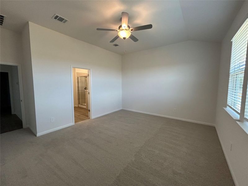 Unfurnished bedroom featuring vaulted ceiling, a ceiling fan, and light colored carpet
