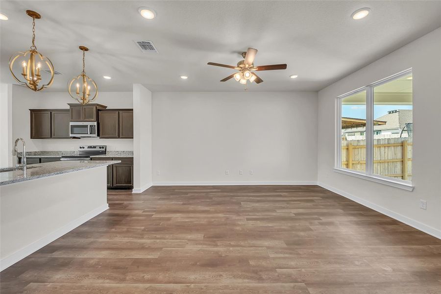 Kitchen with dark brown cabinetry, hanging light fixtures, stainless steel appliances, light stone counters, and recessed lighting Kitchen with dark brown cabinetry, hanging light fixtures, stainless steel appliances, light stone counters, and recessed lighting